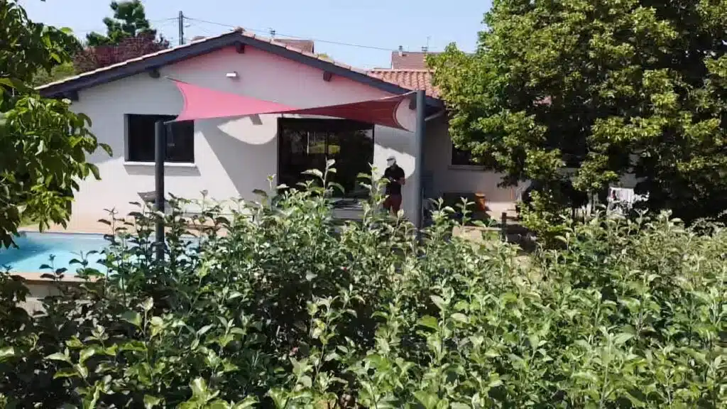 Vue extérieure d’une voile vrillée rouge profond Soltis 92 couvrant une terrasse à Vaugneray (69)