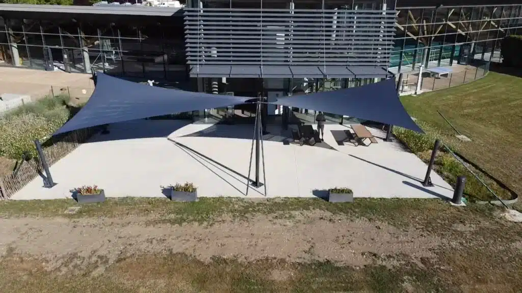 Grandes voiles vrillées gris anthracite en toile Australe ombrageant la terrasse du centre nautique de Genilac