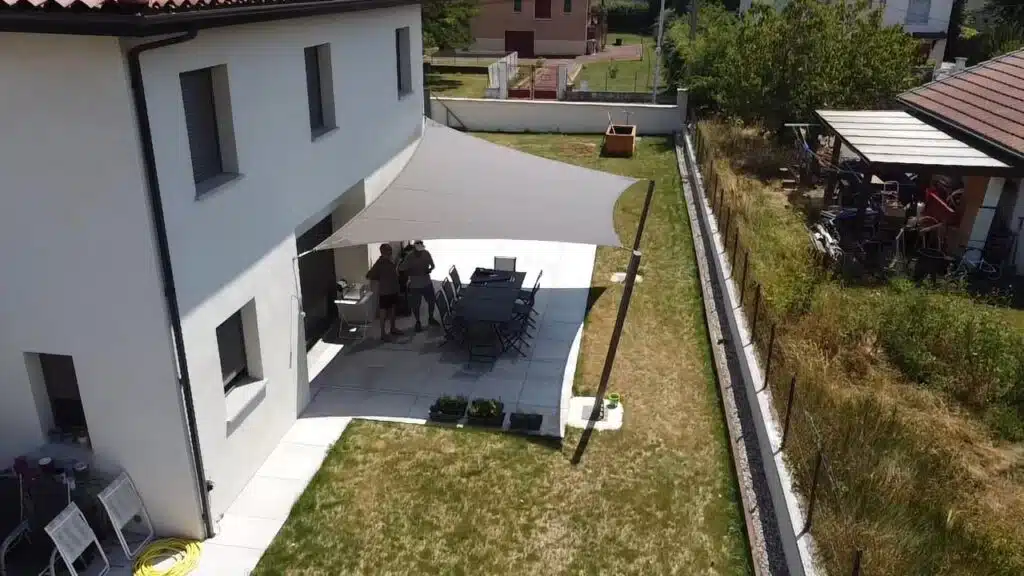 Vue latérale de la voile bronze au-dessus de la table extérieure, offrant une ombre élégante.