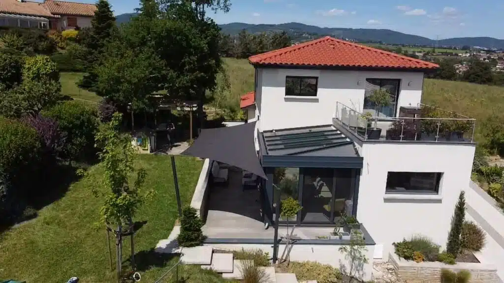Voile d’ombrage vrillée en toile Soltis 92 bronze protégeant une terrasse et une véranda à Brindas dans le Rhône