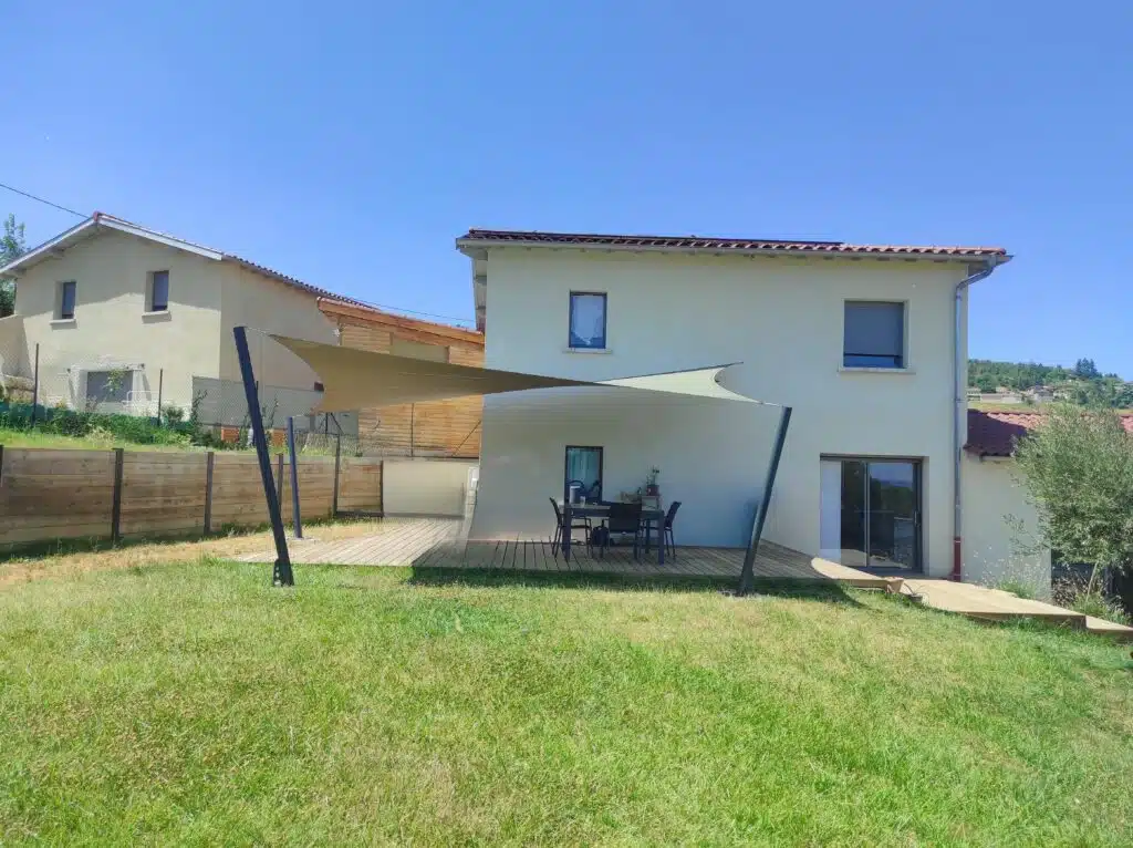 Voile d’ombrage vrillée sur mesure protégeant une grande terrasse à Pollionnay dans l’ouest lyonnais