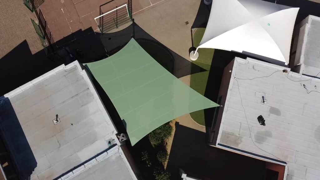 Grande voile d’ombrage vrillée Soltis vert mousse 86 dans une école à Francheville 69